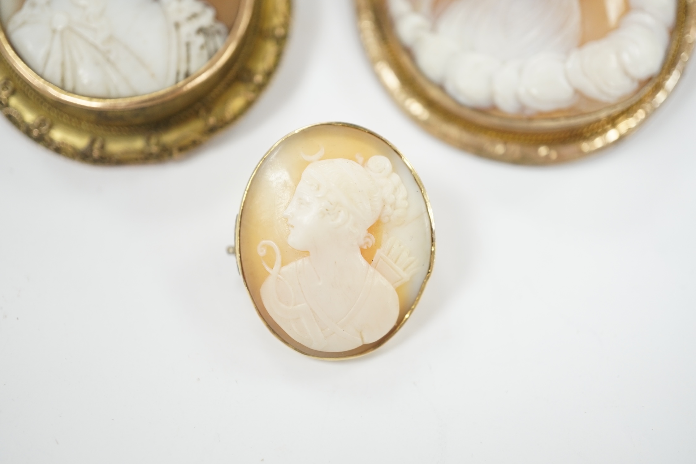 Two yellow metal mounted oval cameo shell brooches, the largest depicting Diana and the Eagle, 55mm and one other gilt metal mounted oval cameo shell brooch.